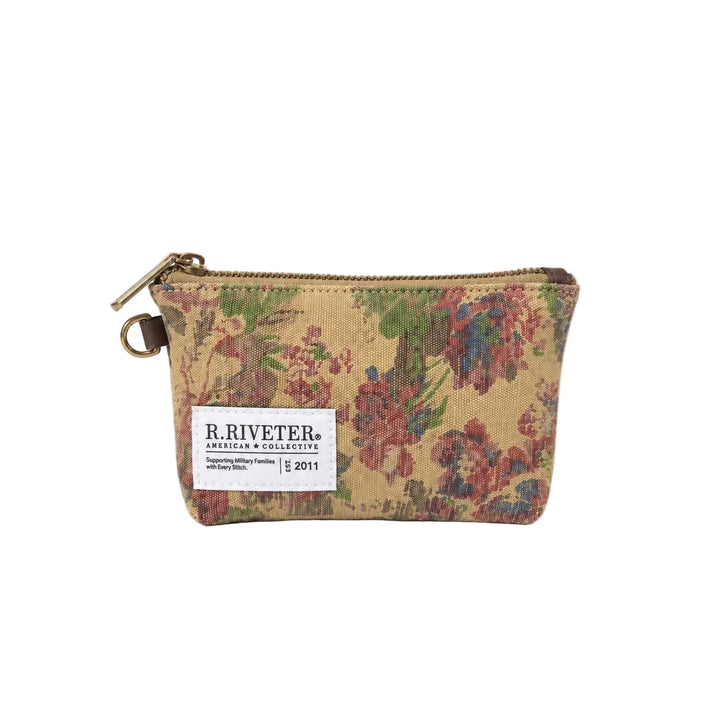 A small zippered pouch by R. Riveter American Collective, featuring a vintage floral tapestry pattern in warm beige, red, green, and blue tones, with a white brand label on the front.