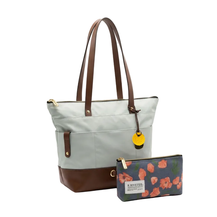 Light blue tote bag with brown accents and a matching pouch with floral design on a white background
