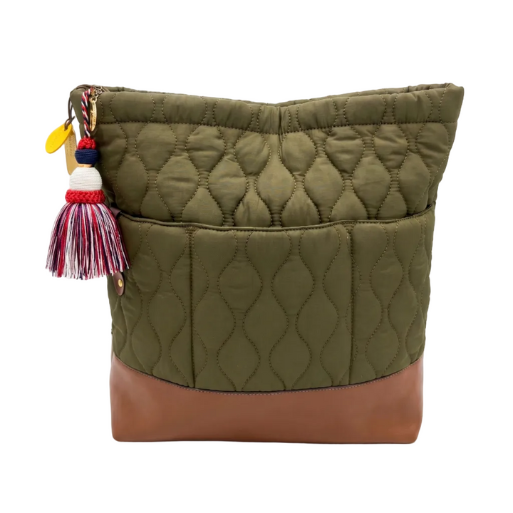 Green quilted bag with a brown bottom section and colorful tassel on a white background