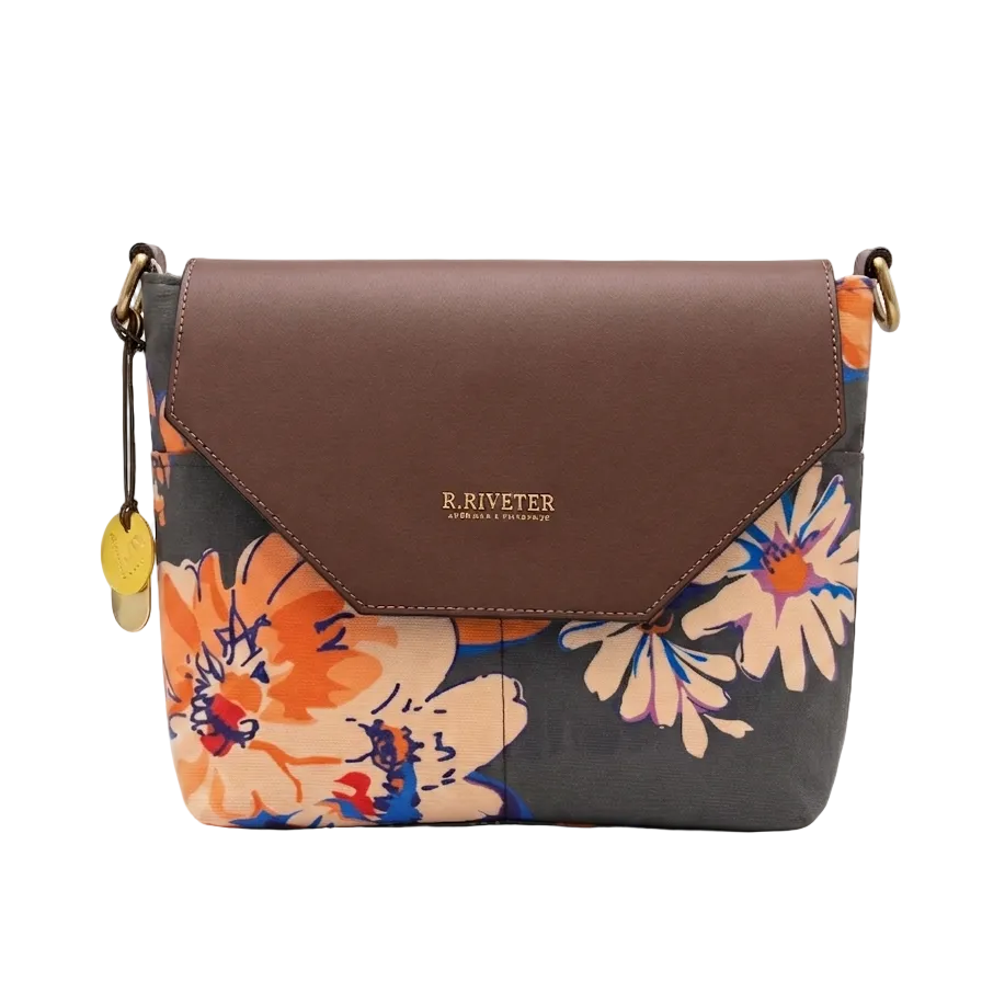 Floral patterned handbag with brown leather flap on a white background