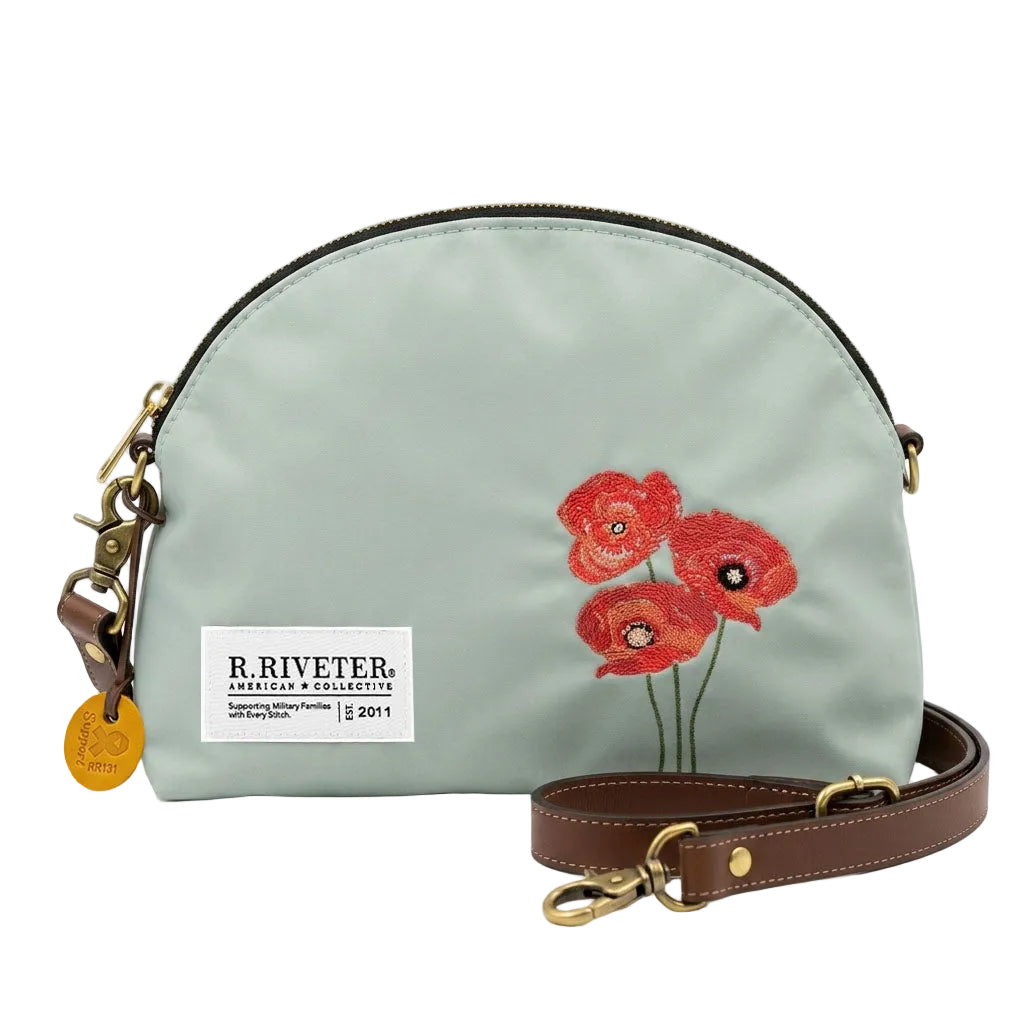 Light blue handbag with red floral design and brown strap on a white background