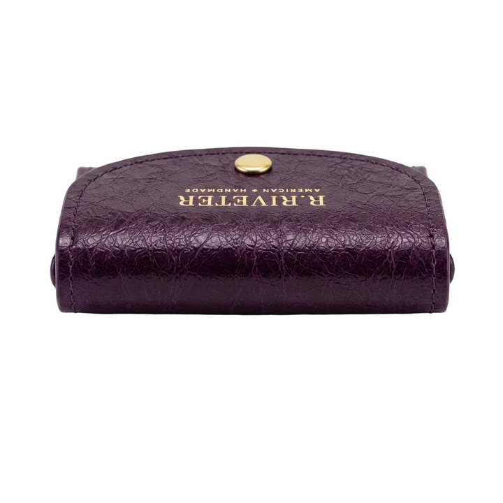 A small purple leather card case with a gold snap button and gold embossed 'R. RIVETER' branding on the front, shown against a plain white background.