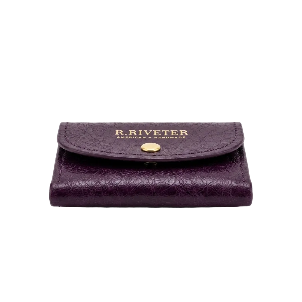 A dark purple textured leather wallet with a gold-tone snap button and gold embossed 'R. RIVETER' branding on the front flap, set against a plain white background.