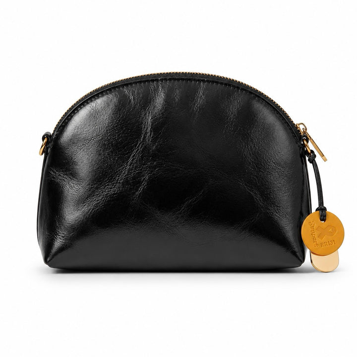 A black leather cosmetic pouch with a curved top and gold-tone zipper pulls, featuring a hanging round gold tag on a white background.