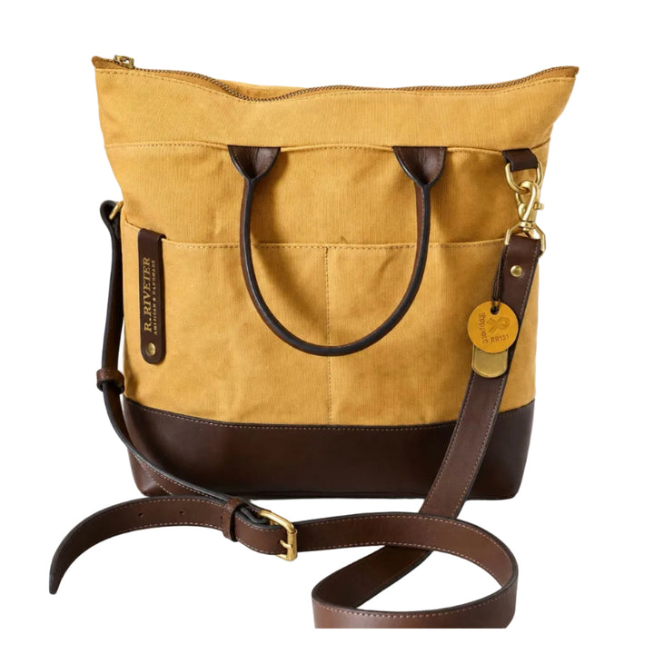 A yellow canvas tote bag with dark brown leather trim, double top handles, a detachable shoulder strap, and gold-tone hardware, shown on a white background.