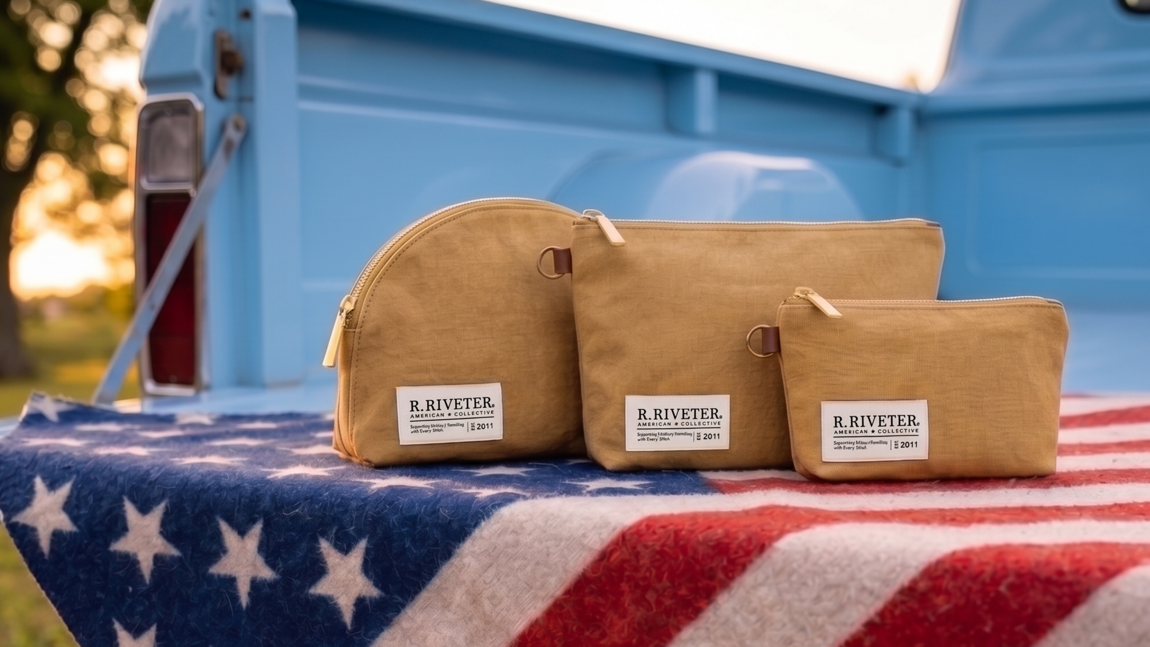 Three beige pouches with 'R. Riveter' branding on a blue truck bed with an American flag.