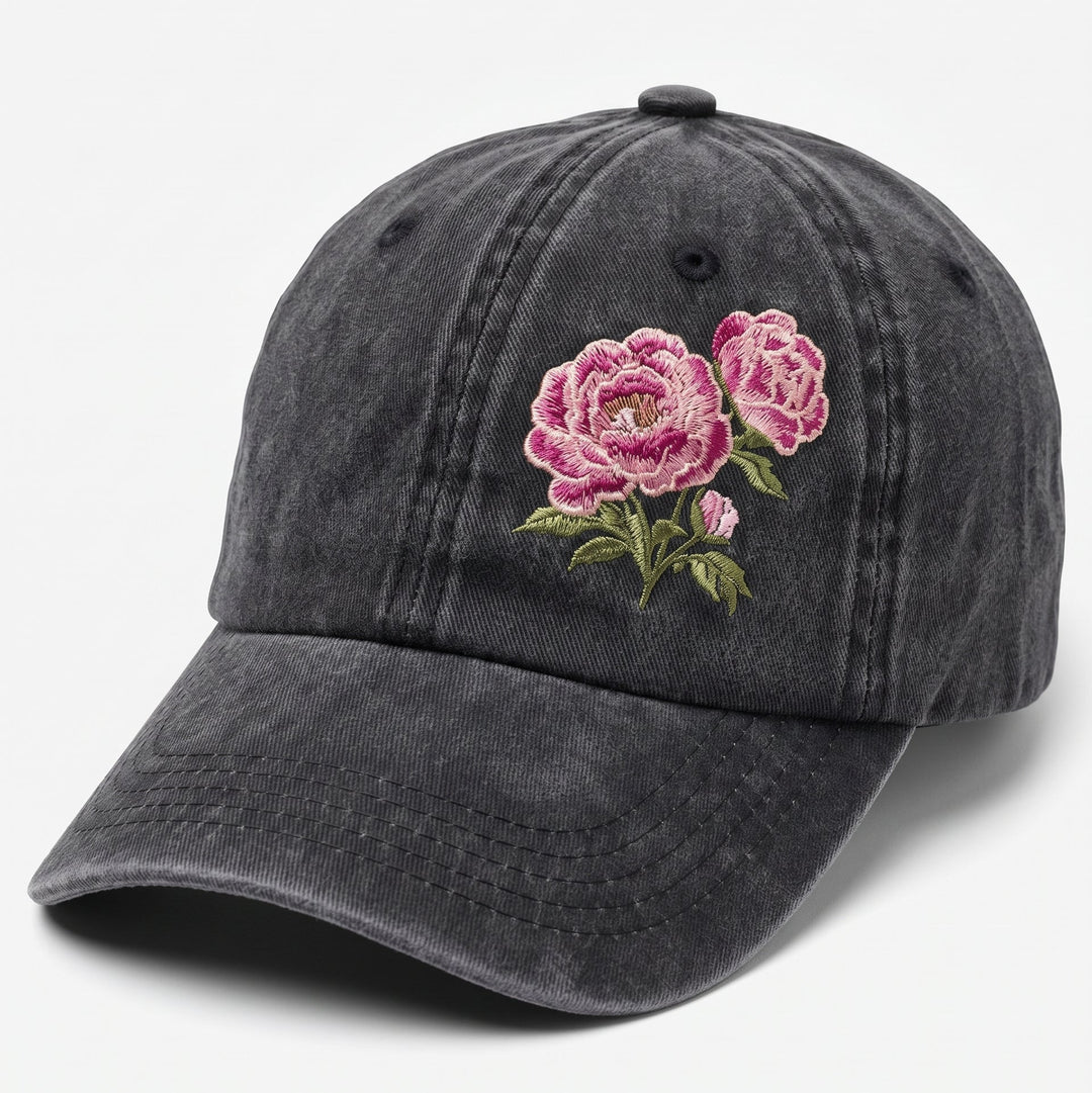 A dark gray washed cotton baseball cap featuring embroidered pink roses with green leaves on the front, set against a plain light gray background.