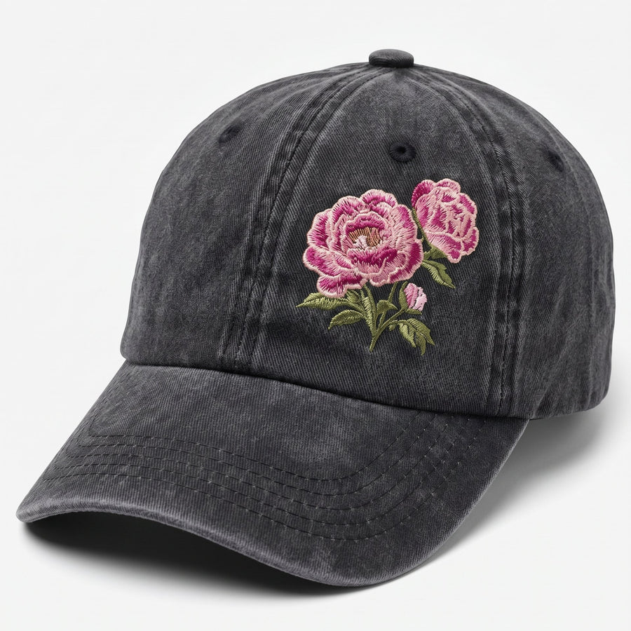 A dark gray washed cotton baseball cap featuring embroidered pink roses with green leaves on the front, set against a plain light gray background.