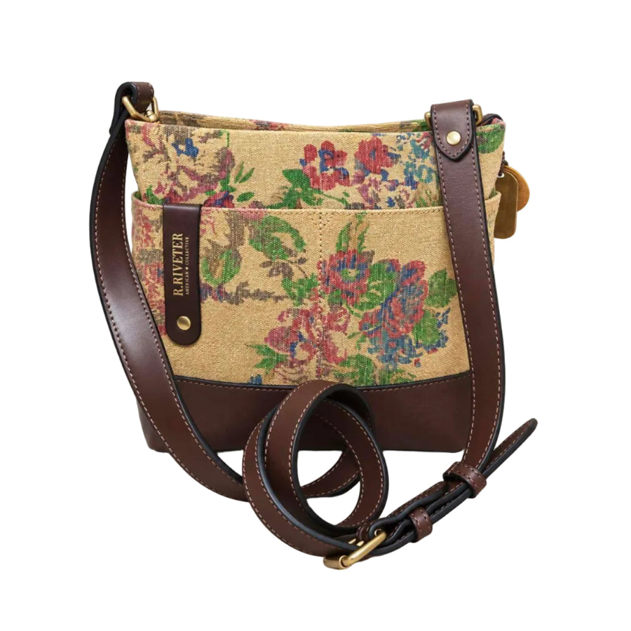 A woven floral bucket bag with dark brown leather trim and a long adjustable shoulder strap, shown on a clean white background. The brand name 'RRIVETER' is visible on a leather tab.