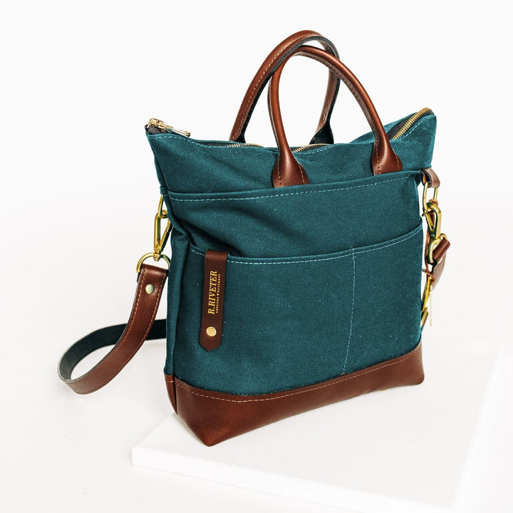 Teal handbag with brown leather accents on a white background